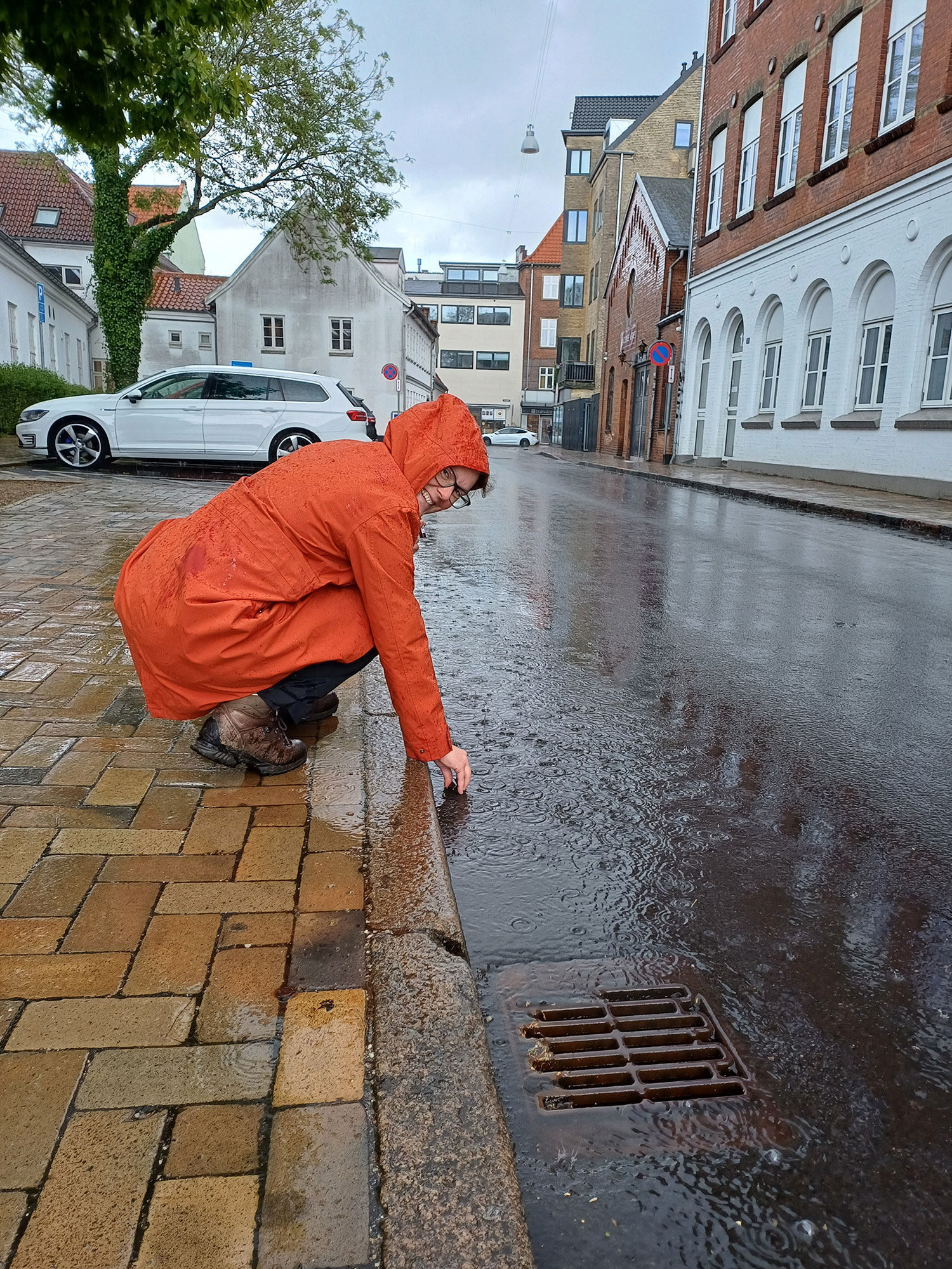 Kvinde tager vandprøve ved fortorvskanten