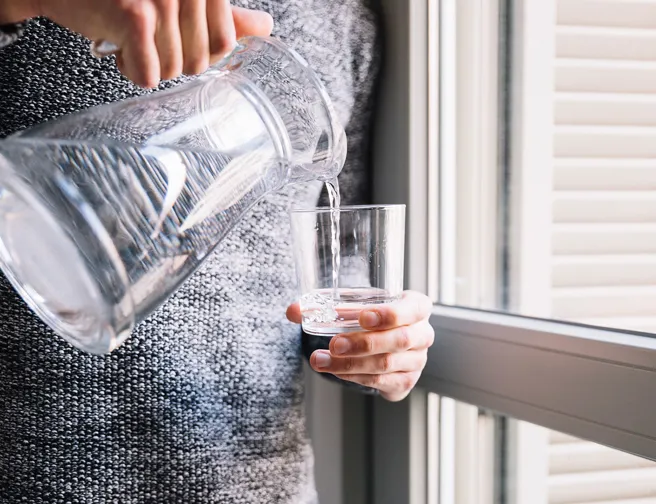 vand skænkes fra kande til glas