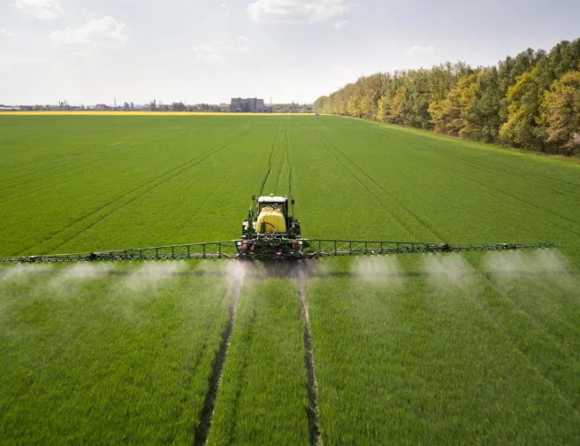Traktor spreder pesticider på mark