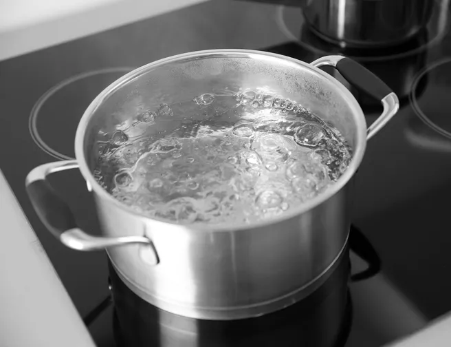 Gryde med kogende vand på komfur