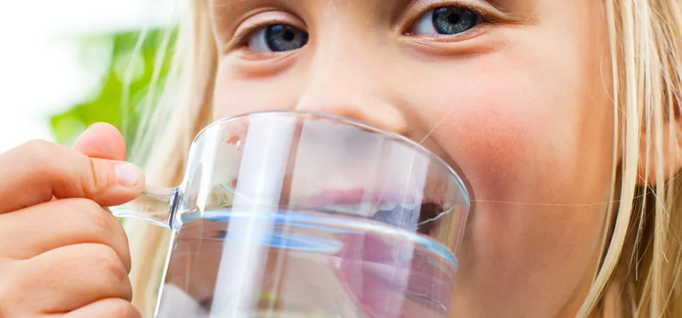 Lille pige drikker vand af stort glas